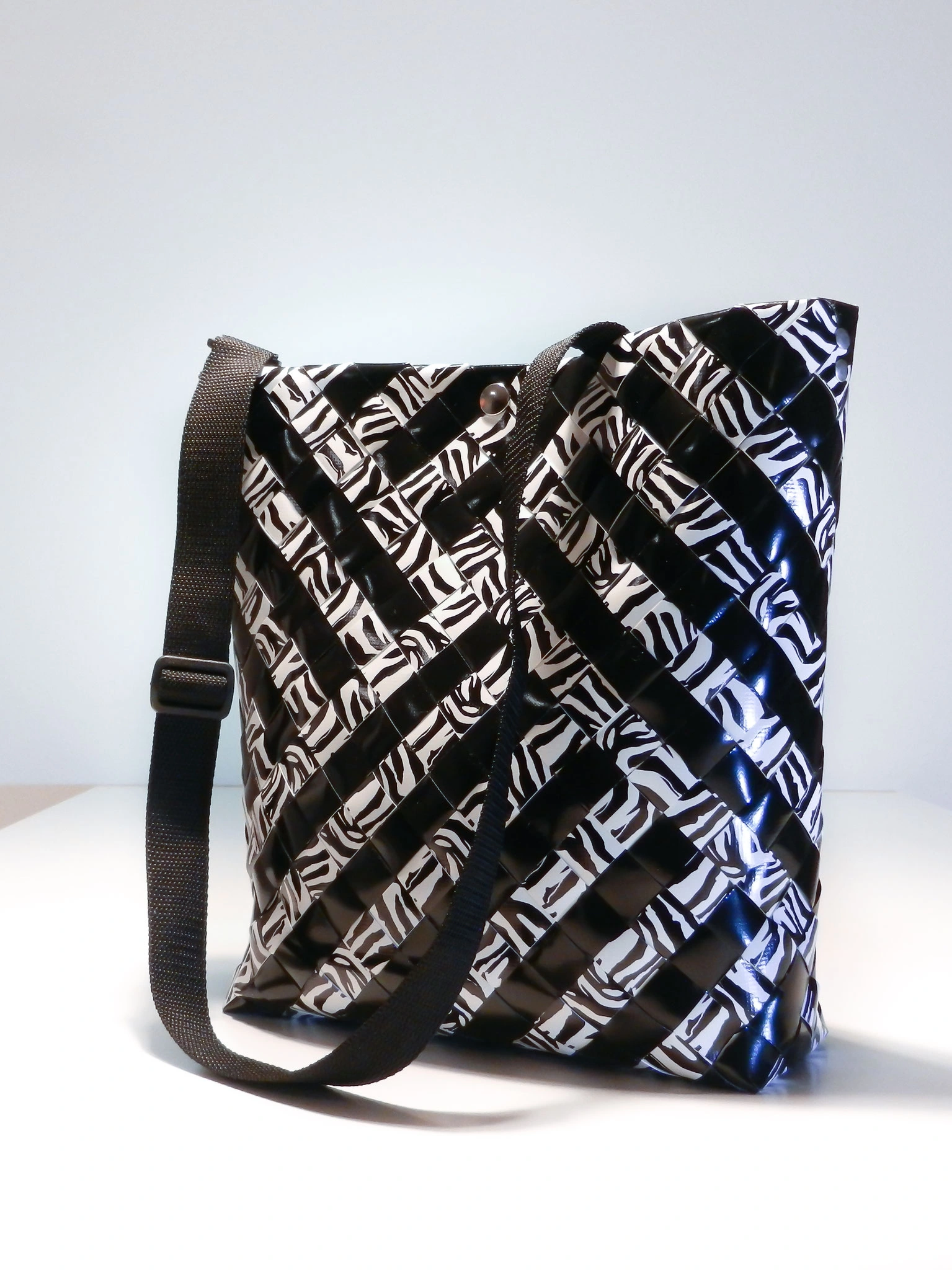 Schwarz-weiße Flechttasche mit Zebra-Muster und schwarzem Schultergurt