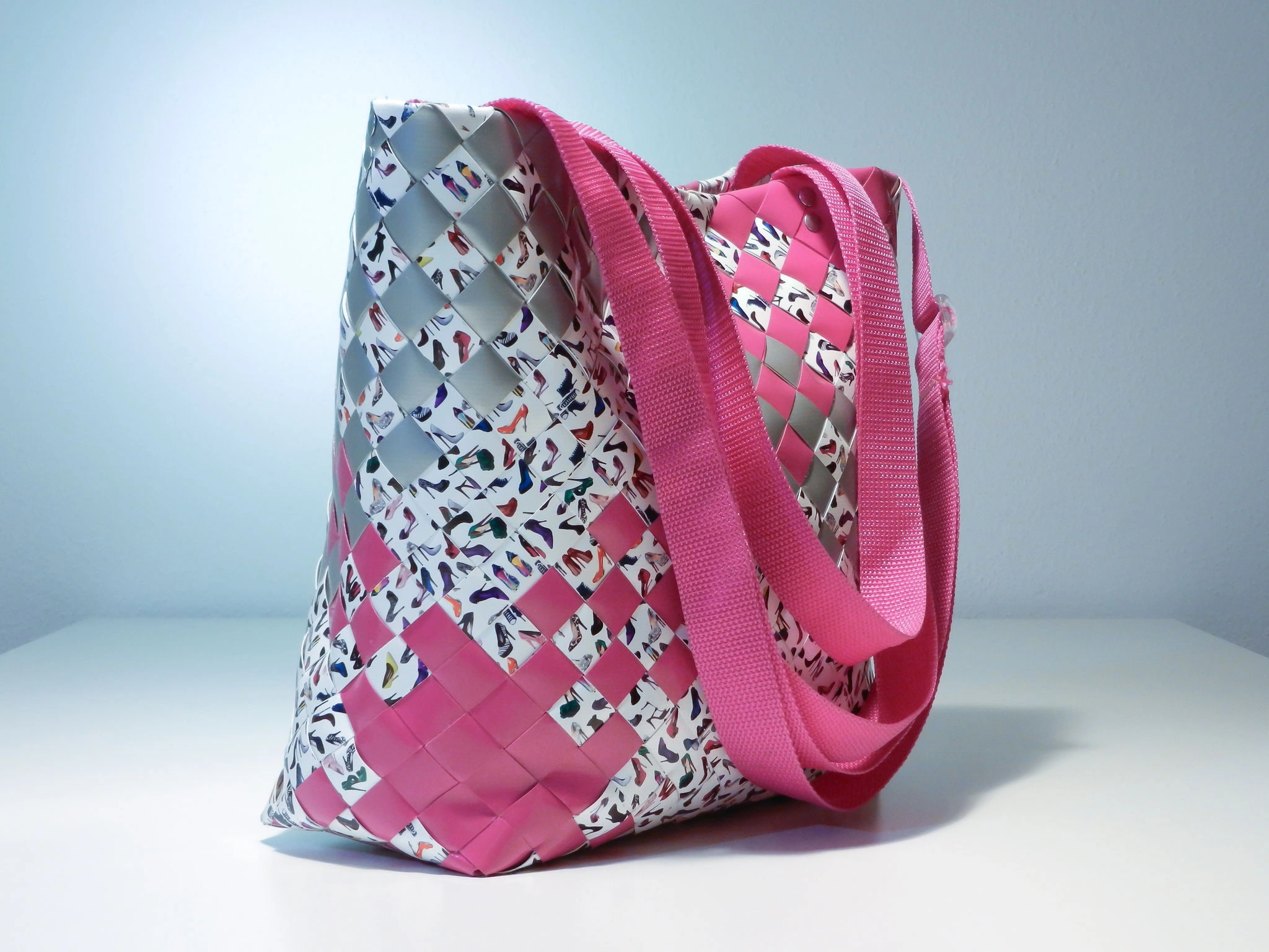 Pink-silberne Flechttasche mit buntem Schuhmuster und pinken Trägern
