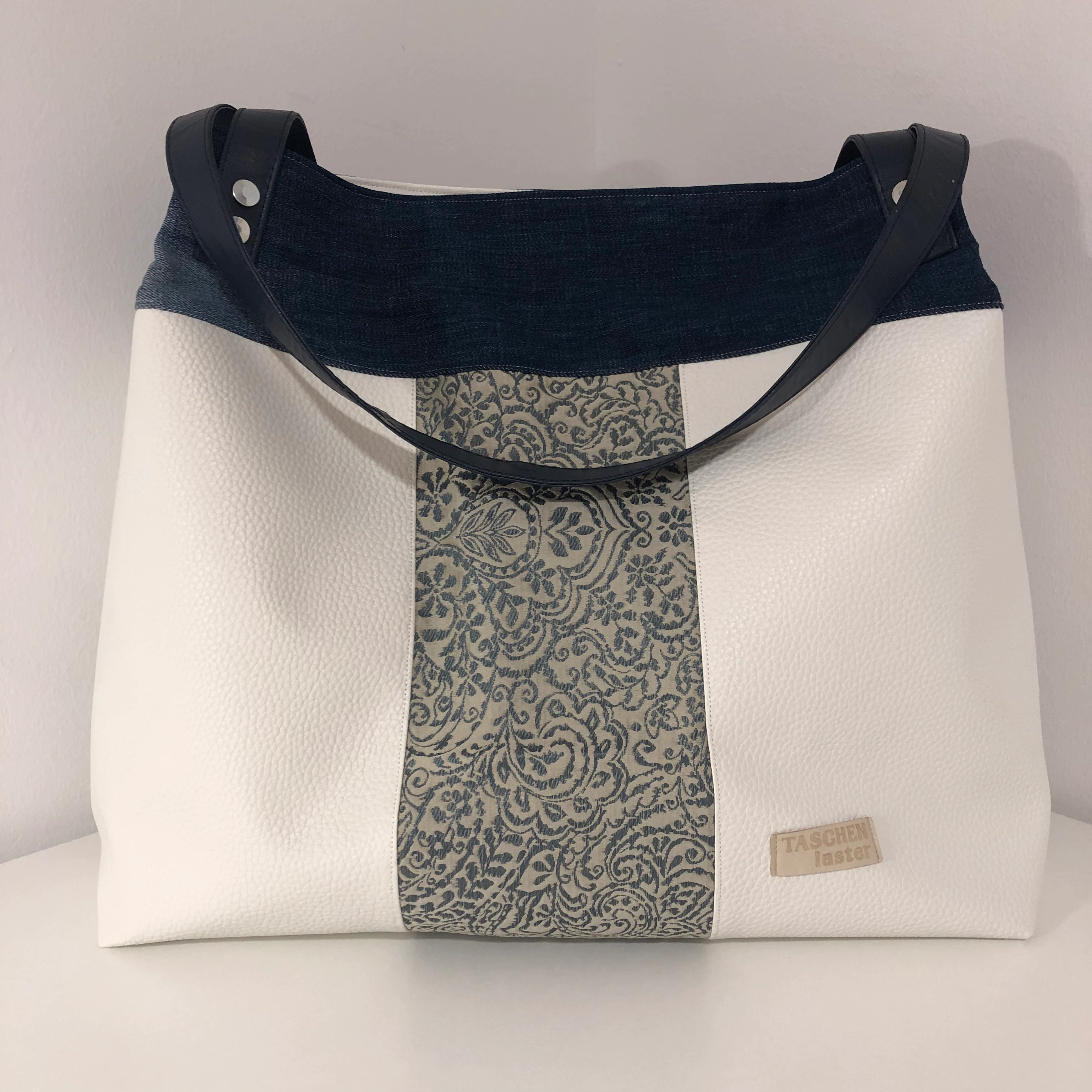 Weiße Aniwaniwa-Tasche mit ornamentalem Motiv, Jeansboden und dunklen Trägern