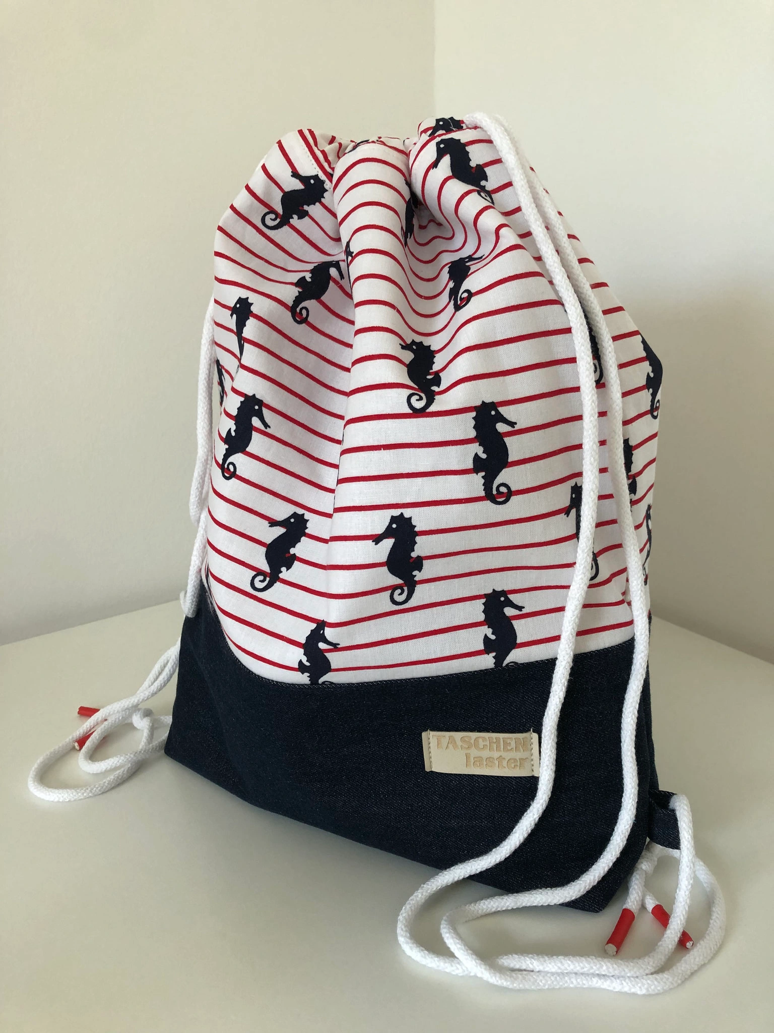 Athena-Zugbeutel mit schwarzen Seepferdchen, roten Streifen und dunklem Jeansboden